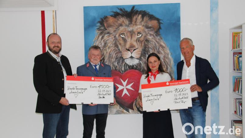 Kinderarzt Roland Renz (rechts) und Landrat Andreas Meier (links) übergeben vor dem Löwenbild mit Malteserherz symbolische Spendenschecks über 1000 Euro an Johanna Lakomski (Zweite von rechts) und 1500 Euro an Dieter Landgraf (Zweiter von links) für die Kinder-Trauergruppe &quot;Löwenherz&quot;. Bild: prh