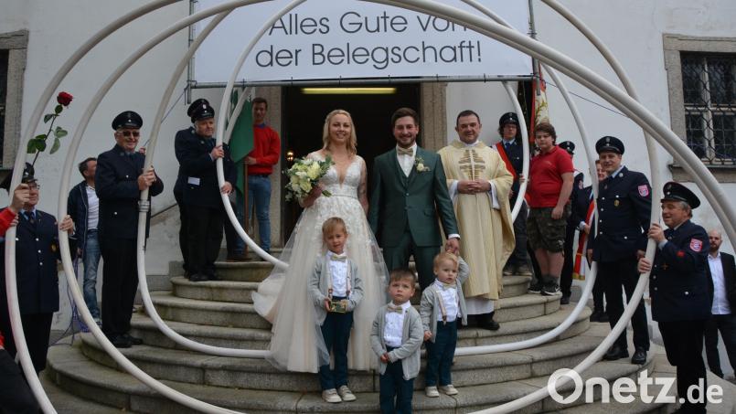 Den kirchlichen Bund fürs Leben schlossen Lena und Bernhard Schuller, hier im Bild mit Bärnaus Stadtpfarrer Konrad Amschl. Als Brautkinder mit dabei waren (von links) Anton, Sebastian und der gemeinsame Sohn Lorenz. Ein Ehrenspalier bildete die Feuerwehr Königshütte, ein Glückwunschtransparent hatten Mitarbeiter der Firma Schuller &amp; Lier vorbereitet. Bild: jr