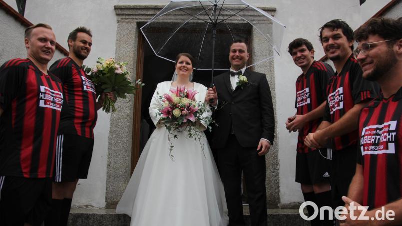 Von den Fußballern der DJK Falkenberg wurden Andrea und Peter Lindner im Ehrenspalier erwartet. Gegen den leichten Regen schützte ein Regenschirm. Bild: kro