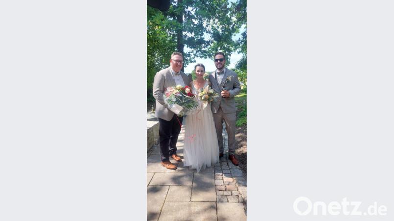 Reinhold (rechts) und Isabell Schellinger aus Kümmersbruck bekamen vom FCB-Fanclub-Vorsitzenden Patrick Kopp (links) zur Hochzeit einen Blumenstrauß in den Farben des FC Bayern. Bild: Patrick Kopp/exb