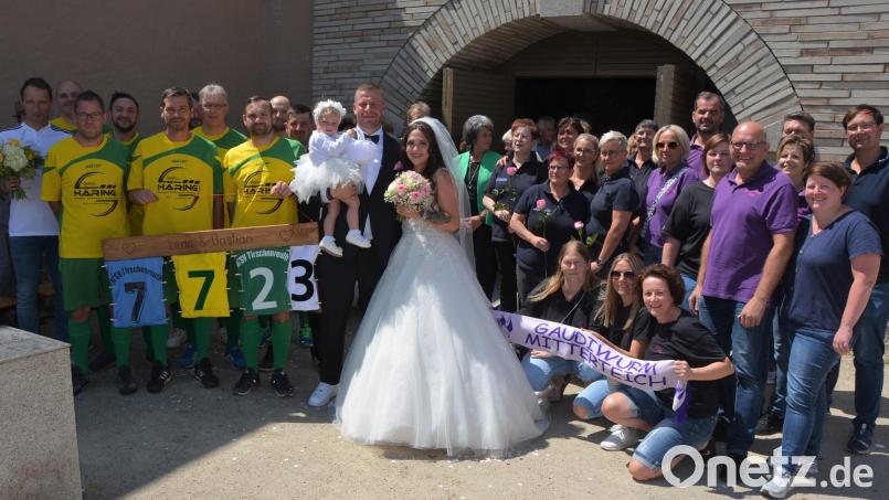 Das Brautpaar Lena Siller und Bastian Freundl mit Tochter Melina im Kreis der zahlreichen Gratulanten, darunter Mitglieder des Mitterteicher Gaudiwurms (rechts), Arbeitskollegen des Bräutigams (Mitte) und die AH-Fußballer des ATSV Tirschenreuth. Bild: jr