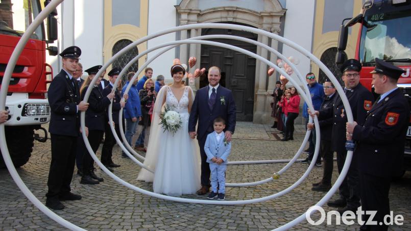 Franziska und Christoph Härtl durchschritten mit dem Brautjungen Devram ein Schlauchspalier, das die Feuerwehren aus Waldsassen und Mitterteich gebildet hatten. Bild: kro