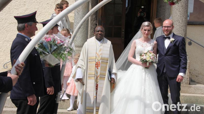 Luisa Schedl und Alex Wölfl wurden nach der Trauung in der Großkonreuther Kirche von der Feuerwehr Dippersreuth im Ehrenspalier erwartet. Links Pfarrer Dr. Charles Ifemeje. Bild: kro