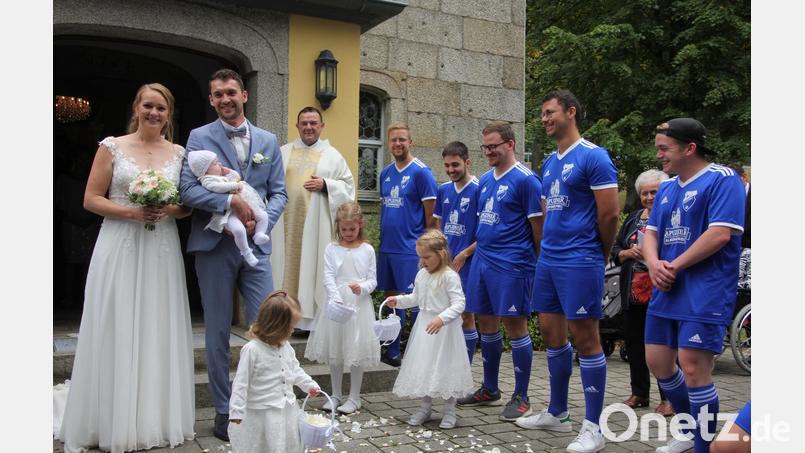 Nadja und Philipp Hopfner gemeinsam mit Töchterchen Anni beim Verlassen der Steinbergkirche. Vorne die Brautmädchen Lea, Lina und Elisa, mit auf dem Bild Pfarrer Konrad Amschl und einige Fußballer der Kondrauer Sportfreunde. Bild: kro