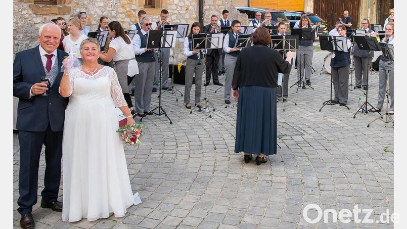 Sieglinde und Hans Geier (links) lassen sich kirchlich trauen. Dirigentin Sabine Kredler (Mitte) von der Werkvolkkapelle Schlicht wünscht dem Brautpaar bei der Übergabe eines Geschenks alles Gute. Bild: Michael Lang/exb