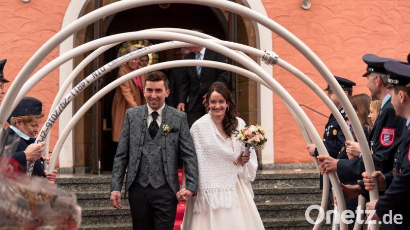 Katja und Johannes Franz schreiten nach der Trauung in Schwend durch das 
Feuerwehrspalier. Bild: sis
