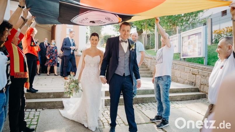 Sebastian Retzer mit seiner Michaela gehen beim Spalier der Flosser Adler unter der DFB-Deutschlandfahne hindurch. Bild: omu