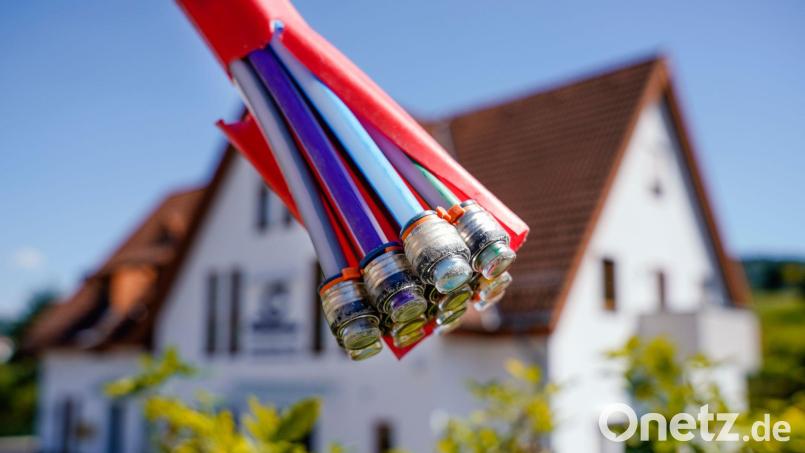 Ein Bündel mit Umhüllungen für Glasfaserkabel hängt vor einem Wohnhaus. Mitte November beginnen Ausbauarbeiten für schnelles Internet in Friedenfels. Symbolbild: Uwe Anspach/dpa
