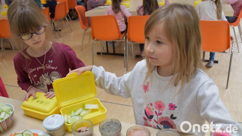 Albina und Pia (von links) schlichten ihre neuen Biobrotzeitboxen mit Biolebensmitteln aus der Region voll. Die beiden Mädchen mögen fast alles, was auf dem Frühstückstisch für Grundschulkinder vorbereitet wurde und greifen zu. Bild: ubb