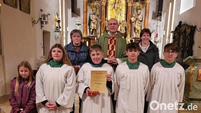 Mesnerin Maria Kühner, Pfarrer Herbert Rösl, Erika Biegerl und Betreuerin der Ministranten in der Expositur (hinten von links) verabschiedeten zusammen mit den Ministranten Peter Biegerl mit Urkunde und Geschenk. Bild: Christa Forster/exb