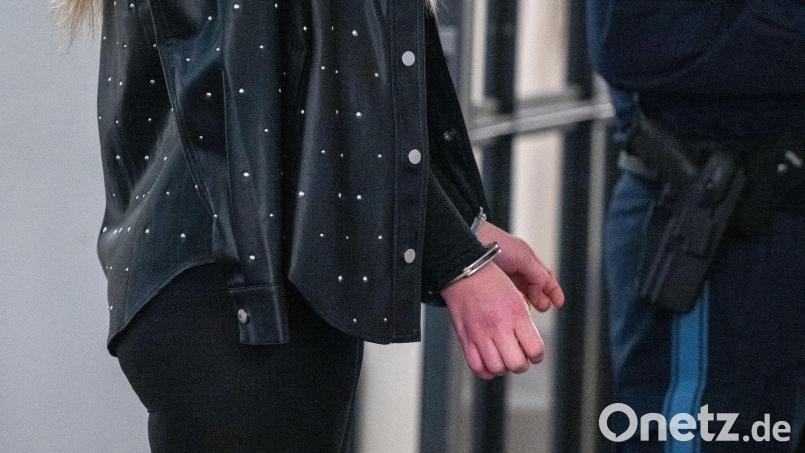 Eine der drei Angeklagten steht mit Handschellen im Flur vor dem Verhandlungssaal des Landgerichts. Bild: Armin Weigel/dpa