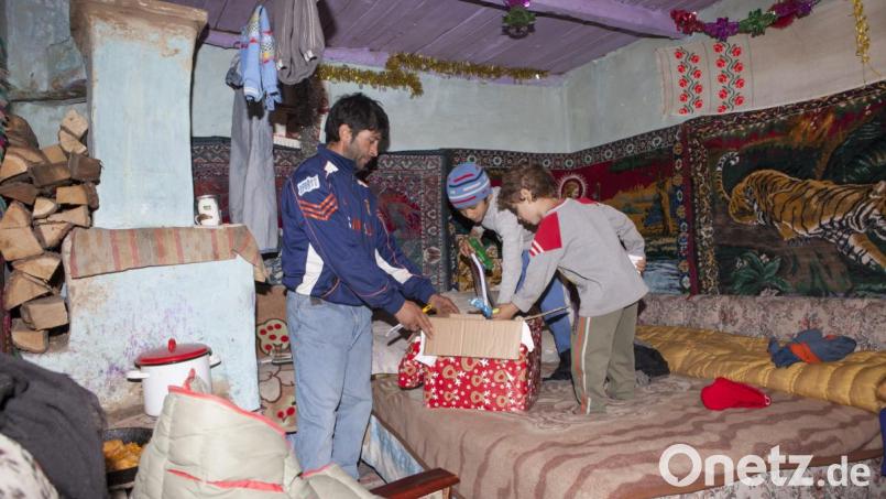 Das Foto ist erschütternd: Zwei gegen die Kälte in ihrer Hütte durch Trainingskleidung notdürftig geschützte Kinder wollen erwartungsvoll sehen, was in einem Geschenkkarton ist. Die Wände der Bretterunterkunft sind mit billigen Teppichen ausgekleidet. Bild: Bauriedl/exb