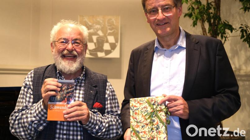 Verleger Fritz Pustet (rechts) bedankt sich bei Autor Alfred Wolfsteiner (links) für die Zusammenstellung der &quot;Kleinen Stadtgeschichte&quot; mit einem Geschenk. Bild: Hirsch