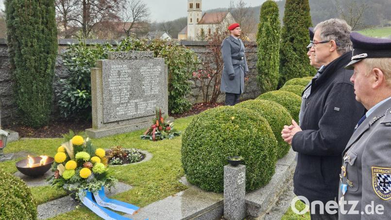 Am Ehrenmal legt Bürgermeister Franz Grabinger zusammen mit Mitgliedern der SKK-Auerbachtal eine Blumenschale zum Gedenken nieder. Bild: ga