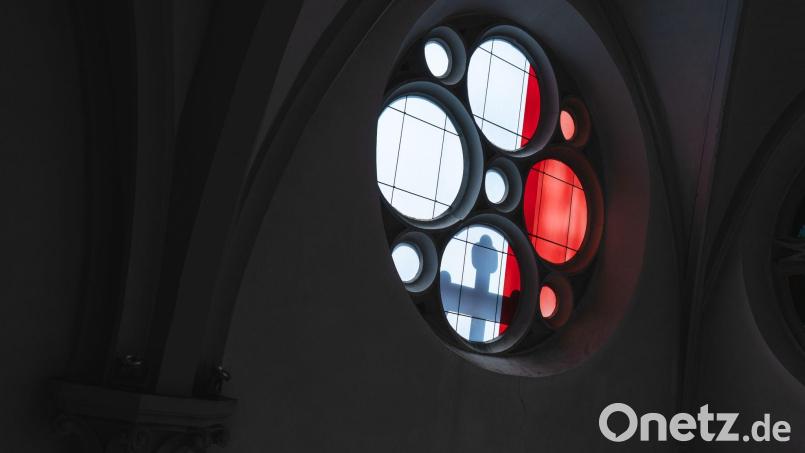 Licht wirft den Schatten eines Kreuzes durch ein Kirchenfenster. Bild: Nicolas Armer/dpa/Symbolbild