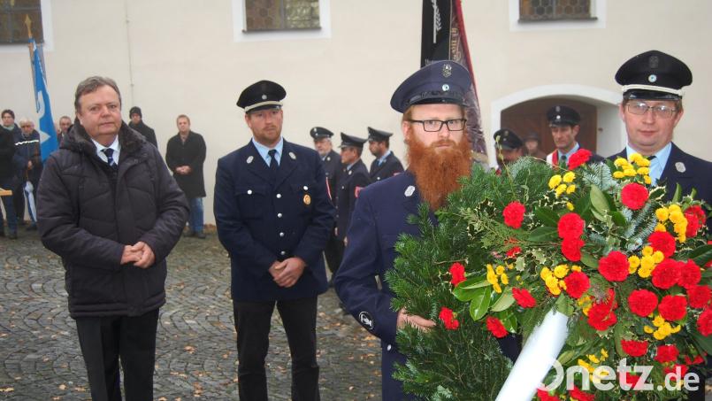 Anlässlich des Volkstrauertages legt Bürgermeister Gerhard Kellner (links) zusammen mit der Feuerwehr am Kriegerdenkmal einen Kranz nieder. Dieser soll Gedenken, Mahnung und Erinnerung zugleich sein. Bild: sm