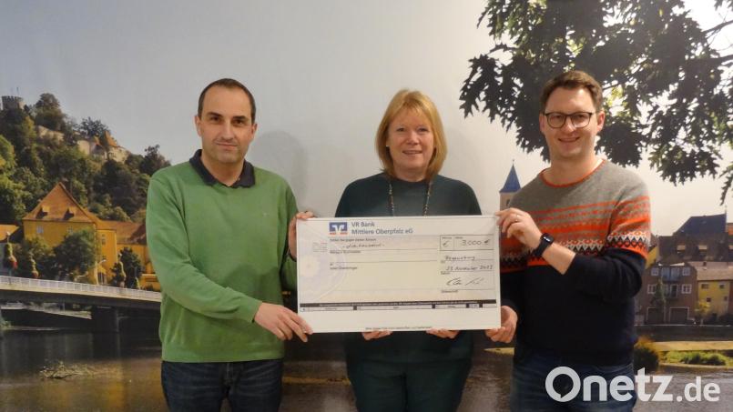 Die Fanhilfe-Vorsitzenden Dieter Keil (links) und Christian Birk (rechts) übergeben den Spendenscheck an Irmgard Scherübl. Bild: Michaela Birk/exb