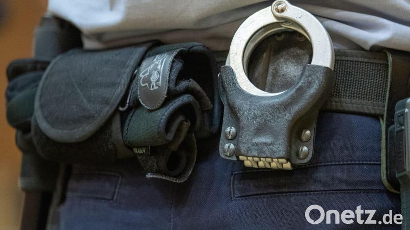 Handschellen stecken in der Gürtelhalterung eines Justizbeamten. Bild: Friso Gentsch/dpa/Symbolbild