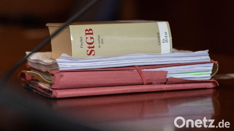 Das Strafgesetzbuch und Akten liegen in einem Gerichtssaal auf dem Tisch. Symbolbild: Swen Pförtner/dpa