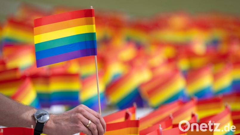 Ein Mann hält ein Regenbogenfähnchen in der Hand. Bild: Monika Skolimowska/dpa/Symbolbild