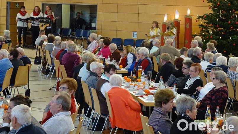 Christkind Joleen Herrmann und Engel Marina Brütting (im Hintergrund von rechts) erfreuten die Senioren mit adventlichen Gedichten. Die Nitzlbucher Frauen (hinten links) übernahmen die musikalische Begleitung. Bild: Sonja Müller