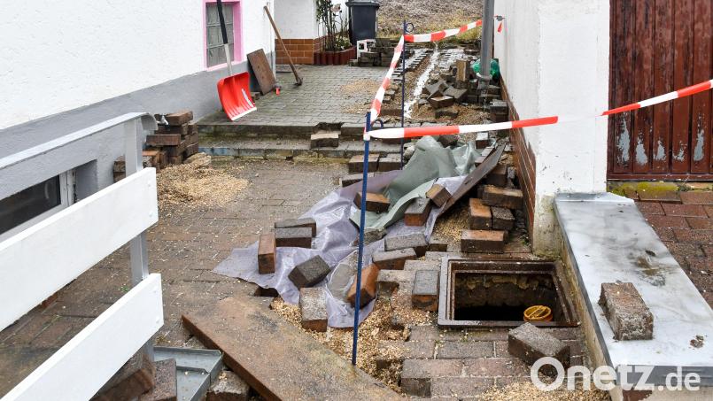 Vom matschig-feuchten Acker (hinten) drückte es das Wasser durch den Kanal und die Hauswände in den Keller von Tobias Trettenbach. In der Nacht rissen die Einsatzkräfte das Pflaster auf, um einen kleinen Entwässerungsgraben anzulegen und das Wasser an der Oberfläche abzuleiten. Bild: Petra Hartl