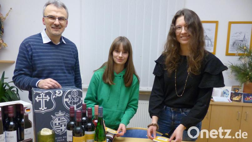 In der Pfarrei Erbendorf wird nach dem Adventssingen am Mittwoch, 27. Dezember, gesegneter Johanniswein verkauft. Pfarrer Martin Besold (von links) sowie die Ministrantinnen Annika Farnbauer und Magdalena Melzner haben die Flaschen mit einem selbst gestalteten Etikett versehen. Bild: Roswitha Heining/exb