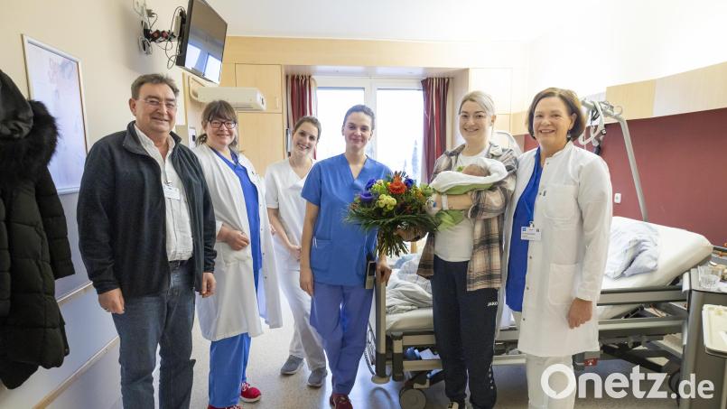 Freudiger Moment der Verbundenheit: Chefärztin Dr. Susanne Merl, Hebamme Celine Michalke, stellvertretende Stationsleitung Anna Prey, Assistenzärztin Christine Schröppel sowie Michael Enzmann, stellvertretender Geschäftsführer m(von rechts) , gratulieren der Mutter Jaqueline Gottfried (Zweiter von rechts) mit Baby Mia mit einem Blumenstrauß. Bild: Michael Vogl/exb