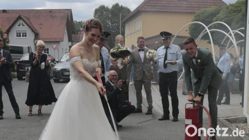 Nach der kirchlichen Trauung erwartet Sarah und Fabian Scharf eine große Schar von Gratulanten. Darunter auch eine Abordnung der Feuerwehr Unterbruck, die das Brautpaar gemeinsam ein kleines, brennendes Häuschen löschen ließ. Bild: lgc