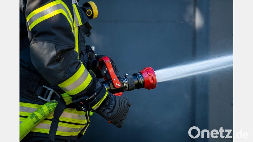 Ein Mitglied der Feuerwehr spritzt aus einem Schlauch mit Wasser. In Edelsfeld war eine Pelletsheizung im Keller eines Einfamilienhauses in Brand geraten. Symbolbild: David Inderlied/dpa/Symbolbild