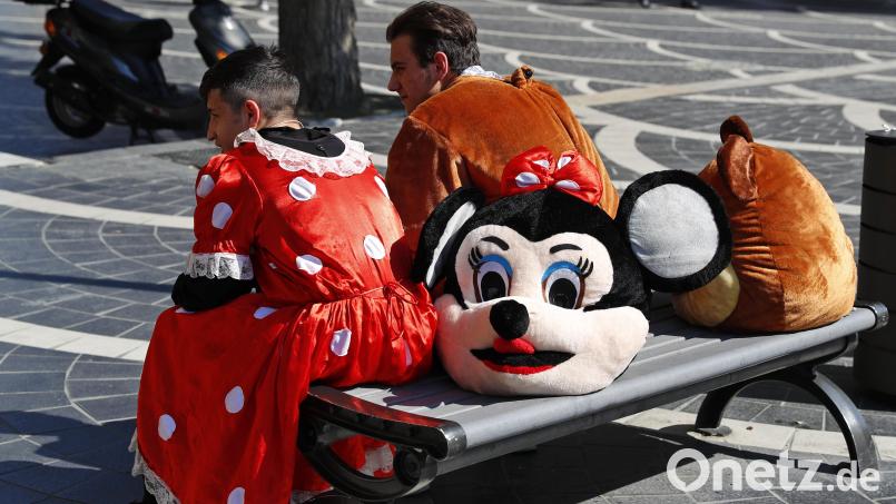 Als Minnie Maus (l) und Puh der Bär verkleidete Straßenkünstler sitzen auf einer Bank. Von Winnie Puh gibt es schon eine Horrorfilm-Version, von Mickey Maus soll bald eine kommen. Symbolbild: Darko Bandic