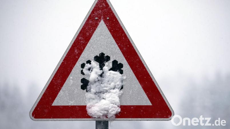 Ein Verkehrsschild, auf dem vor Schnee- und Eisglätte gewarnt wird, ist mit Schnee bedeckt. Glatte Straßen in Amberg und im Landkreis Amberg-Sulzbach hielten die Rettungskräfte und die Polizei auch am Donnerstag auf Trab. Symbolbild: Karl-Josef Hildenbrand/dpa