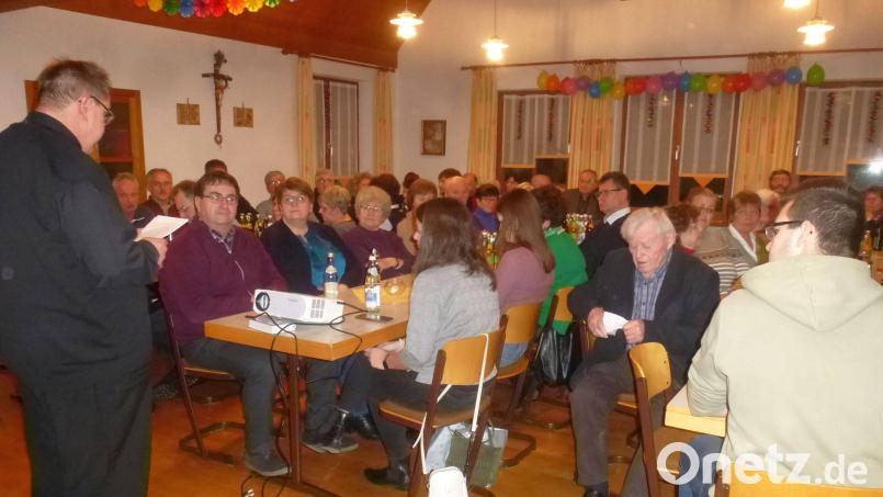Im vollen Pfarrsaal lässt Pfarrer Markus Urban das vergangene Jahr Revue passieren und dankt allen Ehrenamtlichen für ihre Unterstützung. Bild: mad