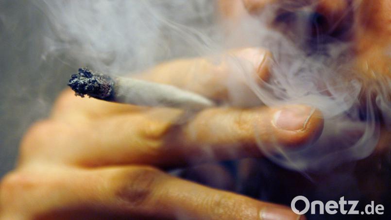 Ein Mann raucht einen Joint mit Marihuana. Darf jemand, der Cannabis zur Schmerzlinderung verschrieben bekommt, unter Einfluss dieser Droge Auto fahren? Diese Frage beschäftigt wieder einmal die Justiz. Archivbild: Daniel Karmann/dpa