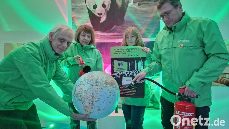 Die Gruppe um Greenpeace will &quot;die Brände auf der Erde löschen&quot;, das symbolisieren sie in diesem Bild. Franz Zielinski hält die Erdkugel. Bild: R. Kreuzer