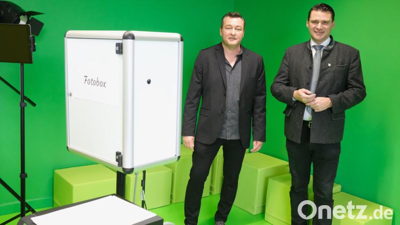 Der Leiter des Medienzentrums Schwandorf, Alexander Friedl (links), erklärt Landrat Thomas Ebeling (rechts) die Funktion der Fotobox. Der neutrale grüne Anstrich der Wände eignet sich besonders gut für eine thematische Hintergrundgestaltung, wie man sie von den Nachrichtensendungen im Fernsehen her kennt. . Bild: Hirsch