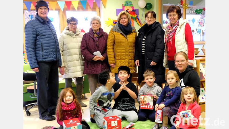 Die Kinder wussten genau, was Tonie-Boxen sind und wollten alles gleich auspacken. Kindergartenleiterin Theresa Schiller (vorne, rechts, knieend) und Pfarrer Berthold Heller (links) freuten sich über die Geschenke, die FU-Vorsitzende Renate Müller (Dritte von rechts) und ihre Vorstandsdamen mitgebracht hatten. Bild: wlr