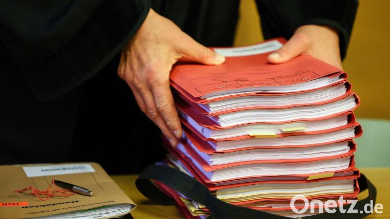 Ein Staatsanwalt legt einen Stapel Akten vor Prozessbeginn auf seinen Tisch im Gericht. Im Prozess um Corona-Maskenbefreiungen und Impfatteste äußert sich jetzt auch der angeklagte Arzt in Amberg. Symbolbild: Jan Woitas/dpa