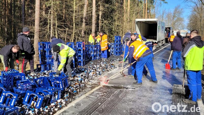 Mitarbeiter räumen Bierkästen und kaputte Flaschen einer von einem Lkw verlorenen Bierladung von einer Straße. Bild: Danilo Dittrich/dpa-Zentralbild/dpa