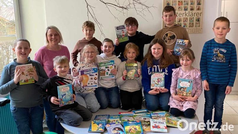 Einige Kinder der Kombiklassen 1/2 und 3/4 und Elternbeiratsmitglied Katrin Koller mit den neuen Büchern für die Schulbücherei. Bild: Grundschule Pechbrunn/exb