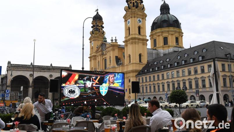 Ein großer Bildschirm steht vor den Stühlen des Cafehaus Tambosi um die Übertragung des Fußballspiels Deutschland - Schweden bei der Fußball-Weltmeisterschaft unter freiem Himmel auf dem Odeonsplatz vor der Theatinerkirche sehen zu können. Bild: Felix Hörhager/dpa
