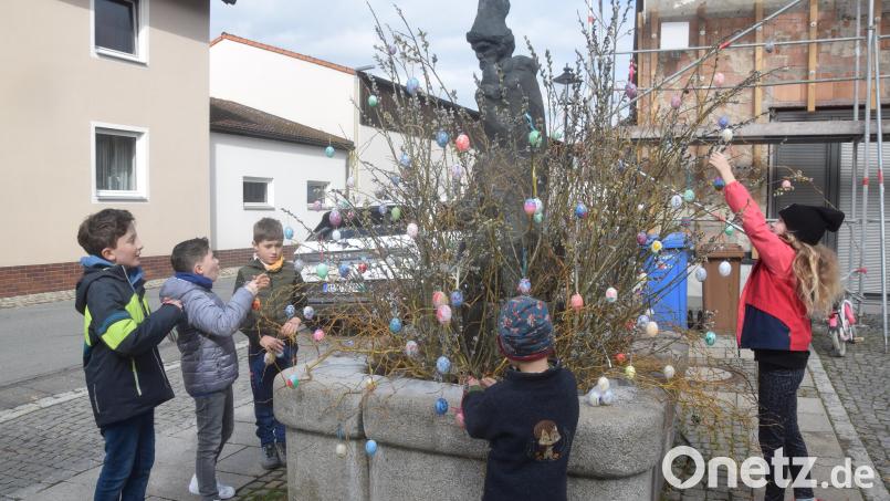 Die Kinder bringen ihre selbst bemalten Eier mit und hängen sie an den Ästen am Florianbrunnen auf. Bild: fz