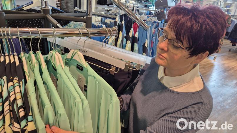 Yvonne Härtl sieht sich die grünen Oberteile auf dem Ständer genauer an: Überall Rußpartikel. Bild: Lowak