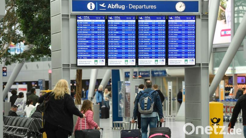 Reisende ziehen ihre Koffer auf dem Flughafen in Richtung Check-In. Bild: Roberto Pfeil/dpa/Archivbild