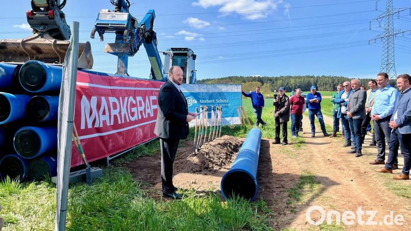 Neustadts Landrat Andreas Meier (links) erklärt bei einem Festakt zum Baubeginn des letzten Abschnitts eines großen Wasserleitungsverbunds Einzelheiten des Projekts. Im Vordergrund ist ein Stück Leitungsrohr mit rund 40 Zentimetern Durchmesser zu sehen. Bild: Gabi Schönberger