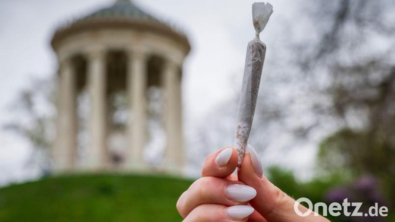 Eine Frau hält einen Joint vor der Kulisse des Monopteros im Englischen Garten. Bild: Peter Kneffel/dpa