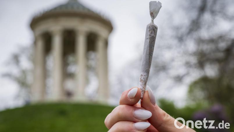 Eine Frau hält einen Joint vor der Kulisse des Monopteros im Englischen Garten. Bild: Peter Kneffel/dpa