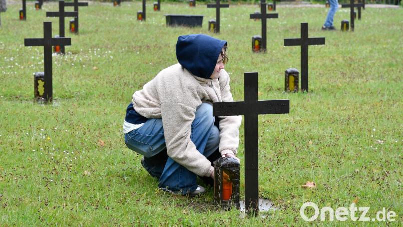 Deutsche und französische Schüler aus der Normandie tauschen am Katharinenfriedhof in Amberg die Kerzen der Kriegsgräber aus. Bild: Petra Hartl
