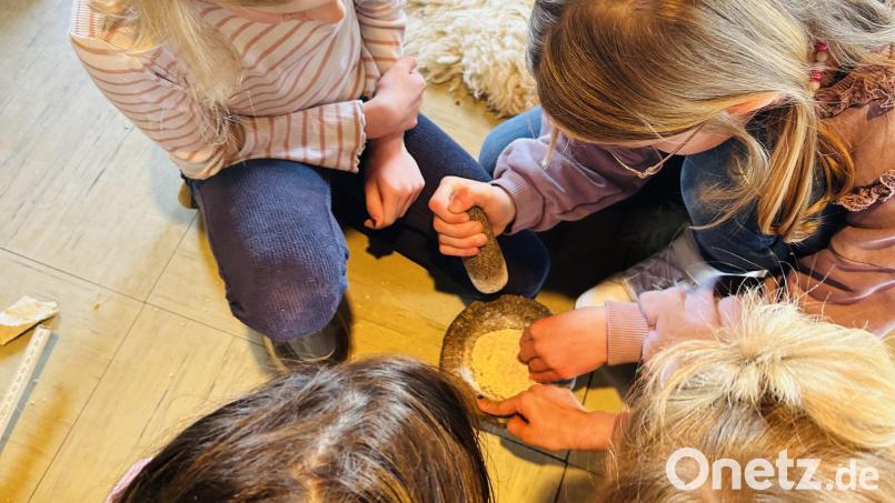 Die Kinder probierten es aus, mit steinzeitlichen Mitteln Getreide zu mahlen. Bild: Ann-Kathrin Förderreuther/exb