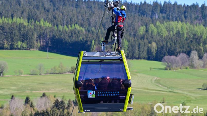 An der neuen Seilbahn am Ochsenkopf stand eine Evakuierungsübung auf dem Programm. Vom Tragseil lässt sich der Bergretter auf das Dach der Gondel ab, öffnet von Hand die Türen und bereitet das Seil zum Ablassen vor. Bild: Florian Miedl/fph